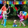 A kertben megtartott gyerekzsúr a középpontban egy színes sárkány formájú papír pinataval 