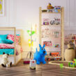 Játékokkal teli gyerekszobában egy kék színű ugráló kutya a háttérben polcokkal