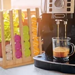 Dolce Gusto kávéfőző mellett elhelyezett kávékapszula tartó állvány színes kávékapszulákkal
