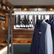 Fémből készült tartórúd egy ruhatároló állványon és az azon elhelyett plüss borítású műanyag vállfák ingekkel