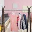 Ruhatartó állványra felakasztott pink gyerek vállfák kisgyermek ruhákkal