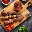 Frissen elkészült grillezett húsok 3 darab grillnyárson egy fa vágódeszkán