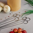 6 darab rozsdamentes acél grillnyárs a konyhaasztalon fűszerekkel körülvéve