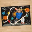 Galaxis mintájú szőnyegen játszó kisfiú 