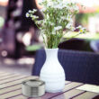 Kültéri rozsdamentes acél asztali hamutartó fehér virágváza mellett a teraszon