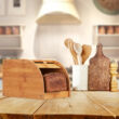 Kisméretű bambuszból készült kenyértartó konyhapulton konyhai kiegészítőkkel a háttérben