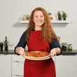Frissen pizzakövön sült pizzát tartó hölgy a konyhájában