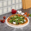 Kompakt méretű pizzakő pizzát tálalva a munkapulton várva azt, hogy kihüljön
