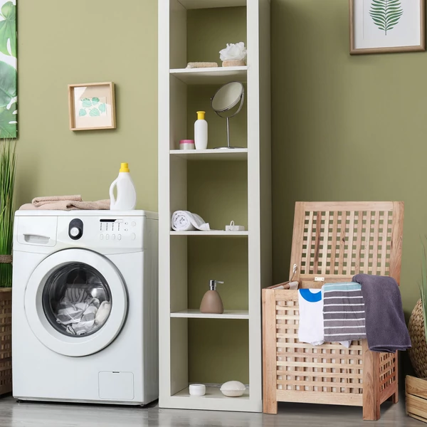 Zöld színű fürdőszobában elhelyezett diófa szennyestartó nyitott tetővel pár darab szennyesruhával