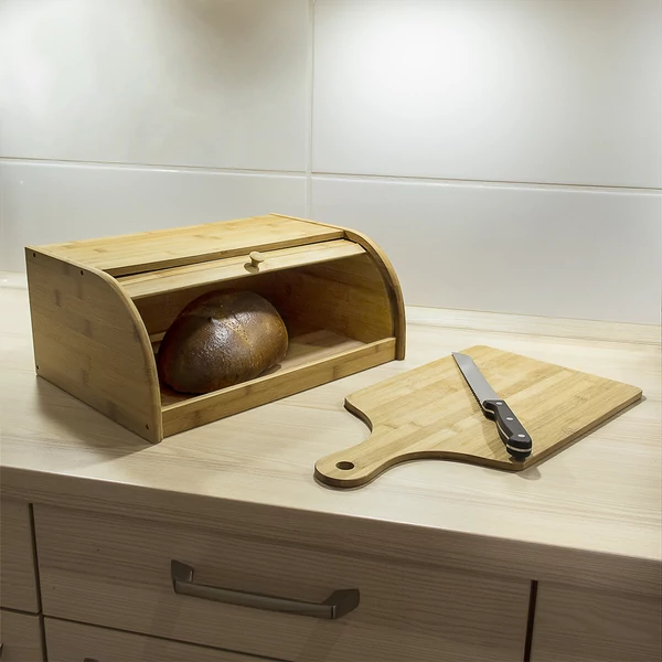normál méretű bambusz kenyértartó lehúzható előlappal egy vágódeszka mellett a konyhapulton