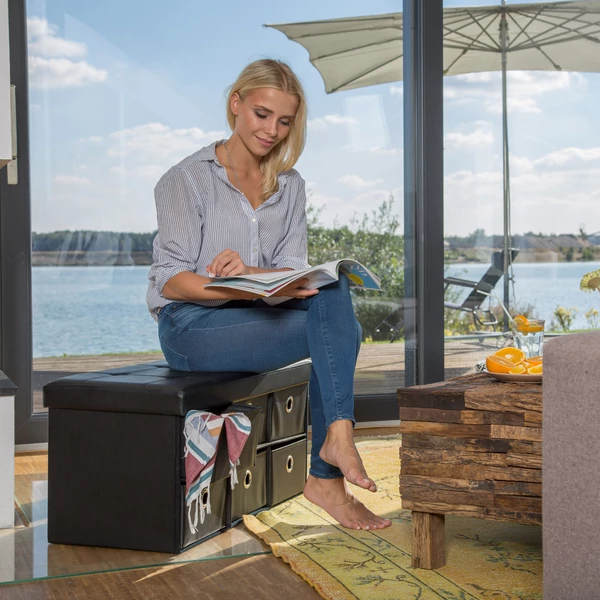 Nadja fekete színű kihúzható tárolódobozokkal felszerelt összecsukható műbőr puff egy teraszon