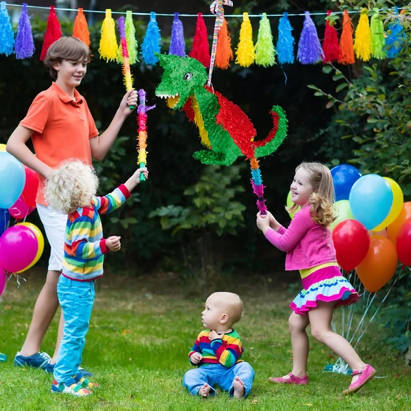 A kertben megtartott gyerekzsúr a középpontban egy színes sárkány formájú papír pinataval 