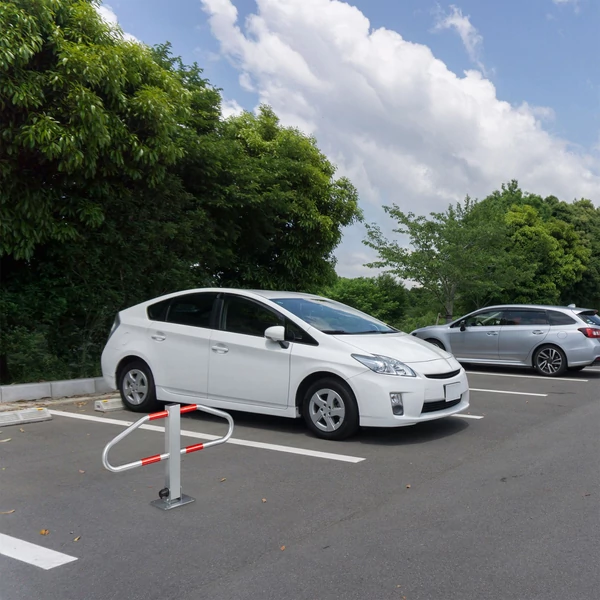 Ledönthető kengyel alakú parkolásgátlóval védett parkolóhely egy fehér toyota prius mellett