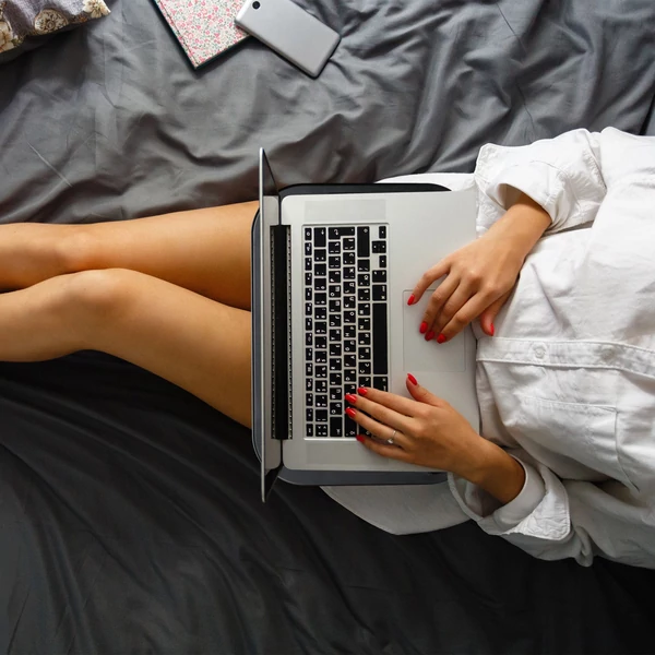 Zipa laptop tartón elhelyezett ezüst színű notebook felületnézetből egy az ágyból dolgozó hölgy ölében