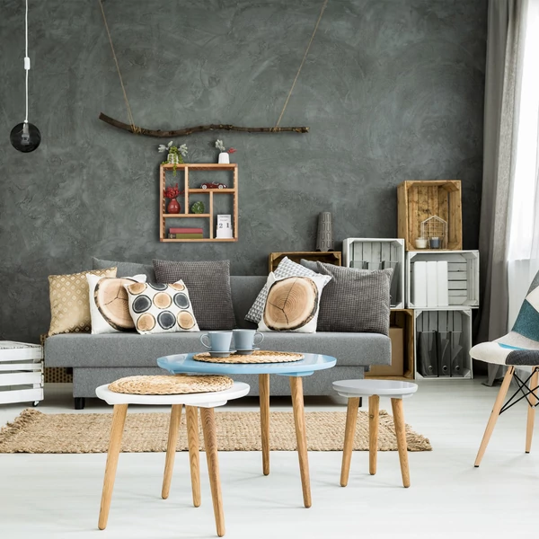 Nappaliban szürkére festett falon a kanapé felett elhelyezett valódi diófából készült fali polc dekorációs elemekkel