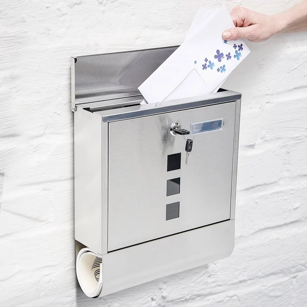 Natúr felületű anyagában rozsdamentes acél kültéri fali postaláda nyitható fedlappal éppen egy benne elhelyezendő levéllel