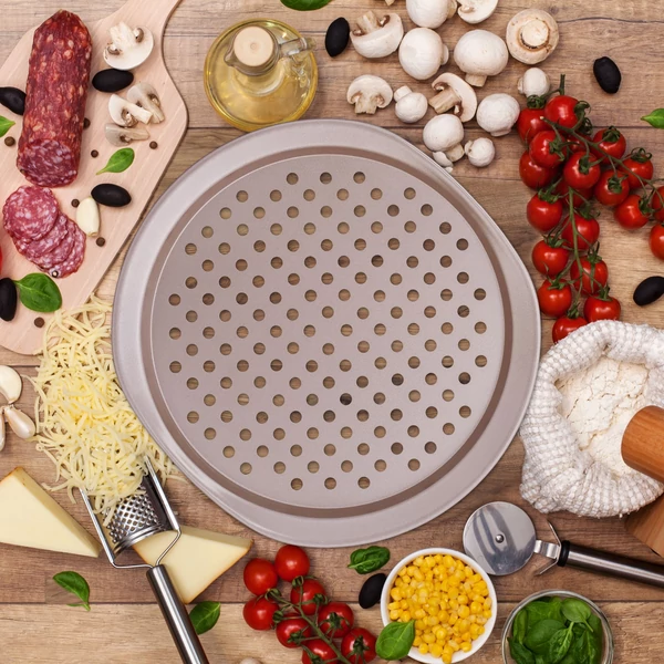 Barna színű pizzakészítő sütőforma a konyhapulton körben feltétekkel