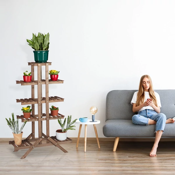 Gunda barna színű fa virágtartó állvány a nappali egyik sarkában egy szürke színű kanapé mellett elhelyezve