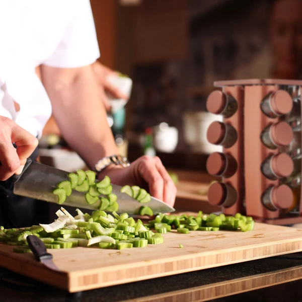 réz színű fűszertároló állvány zöldségaprítás közben a vágódeszka mellett