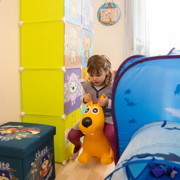 Kislány ahogy  éppen egy ugráló kutya hátán játszik