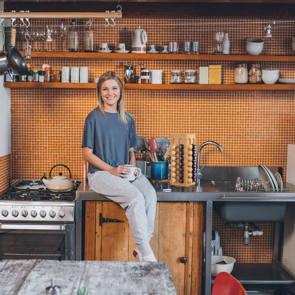 Modern famintás konyha a pulton ülő hölggyel és a munkapulton elhelyezett gépek között egy caffissimo kávékapszulatartó állvánnyal