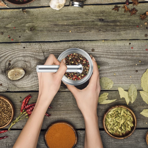 Viszonylag kis méretű rozsdamentes acélból készült 10 cm átmérőjű mozsár fűszerkeverék készítése közben