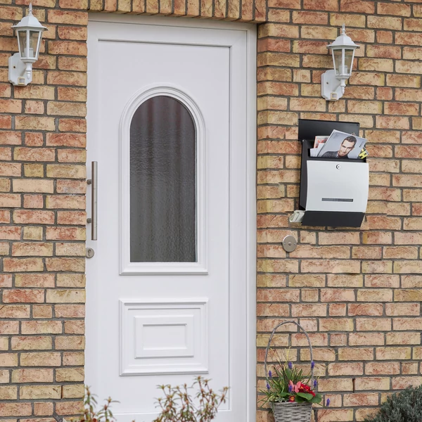Vágott téglával felrakott házfal rajta egy fekete fehér modern filip postaládával