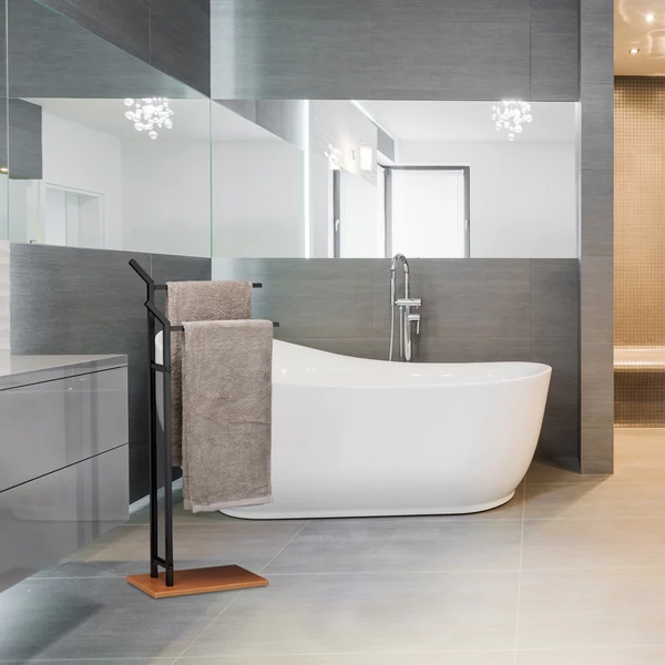 Modern fürdőszobában felállított silkon törölközőszárító állvány szürke törölközőkkel