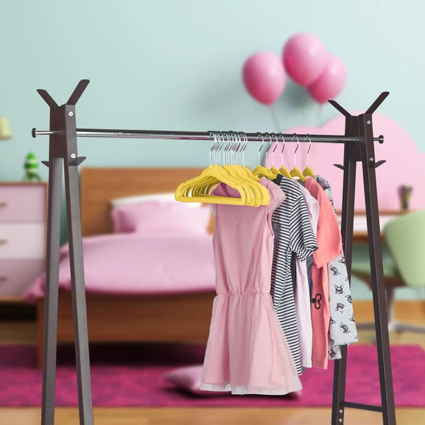 Ruhatartó állványon a gyerekszobában elhelyezett gyermek ruhák sárga plüss borítású gyerek vállfákon
