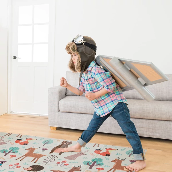 Gyerekszőnyeg erdei állatkás mintával egy krém színű kanapé előtt