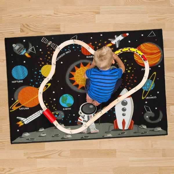 Galaxis mintájú szőnyegen játszó kisfiú 