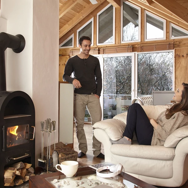 Modern fekete kandalló mellett takarító eszközök arany színben