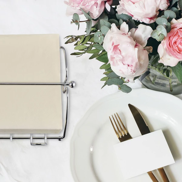 Esküvőhöz megterített bankettasztalon elhelyezett alran magasfényű acél szalvétatartó krém színű szalvétákkal