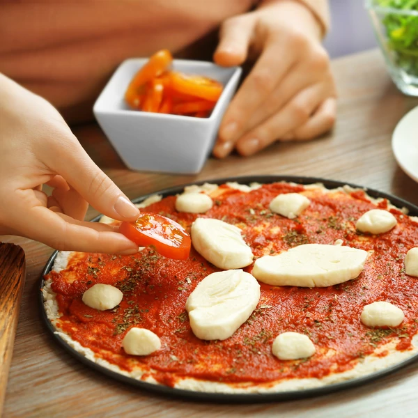 Pizzasütő lapon elhelyezett sütésre kész házi készítésű pizza